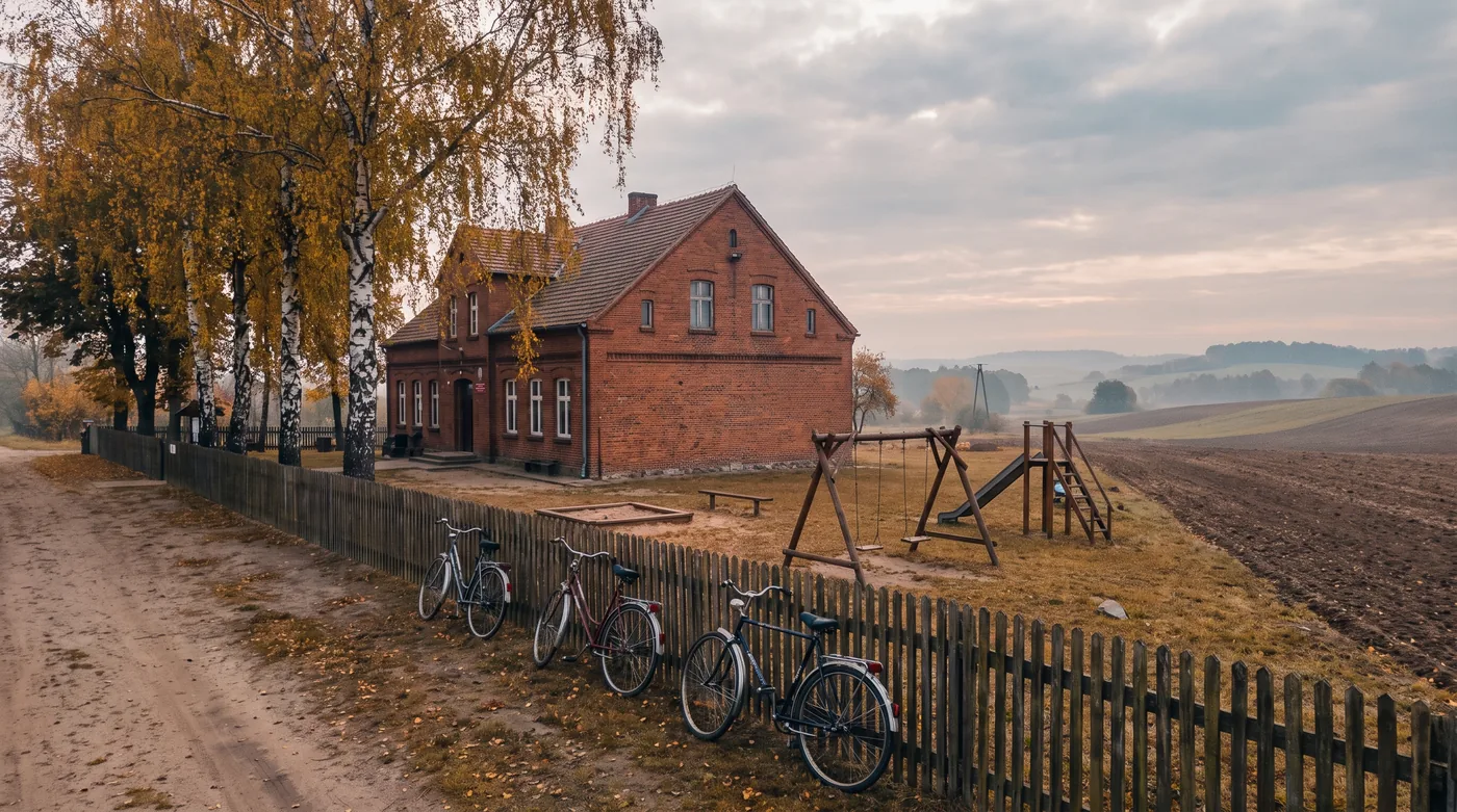 Mała wiejska szkoła podstawowa z ceglanym budynkiem i boiskiem, jesienią